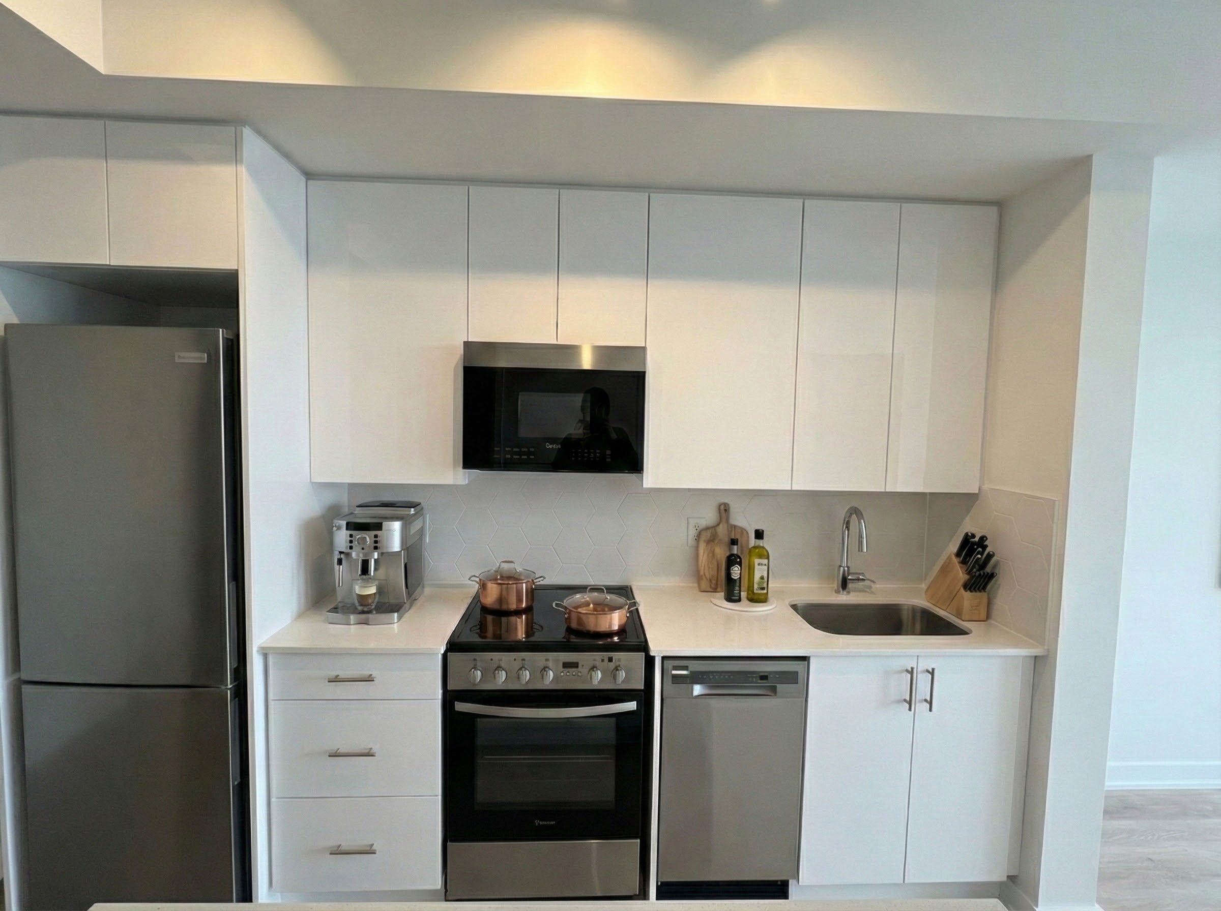 Modern kitchen in Ellie Condos Unit 2611 featuring quartz countertops, integrated stainless steel appliances, and peninsula layout
